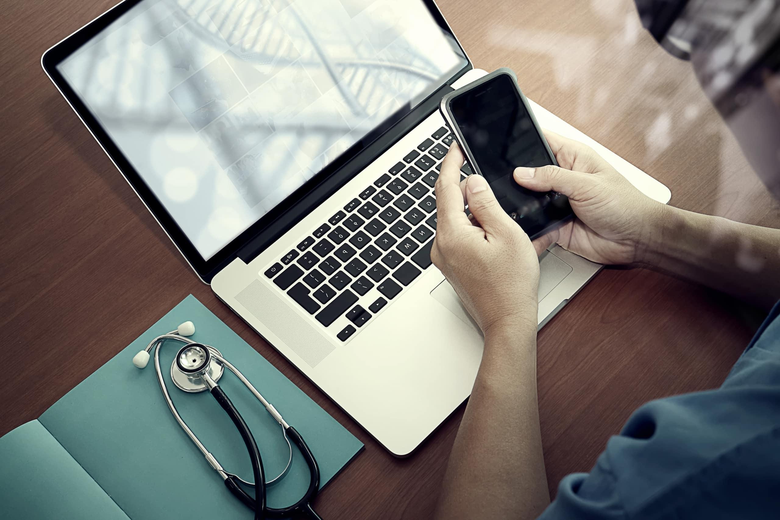 Close up of a medical professional, smartphone, and laptop